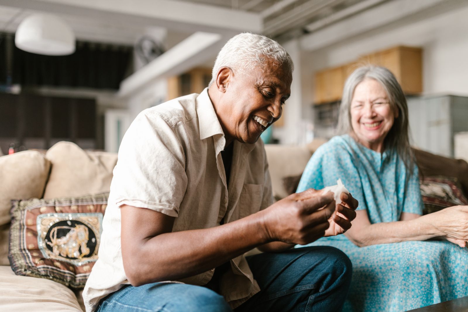 A joyful senior couple sharing a moment of laughter on the sofa in a cozy indoor setting.